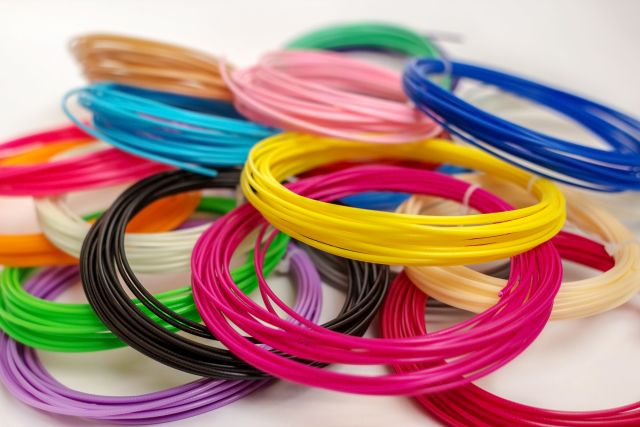 Group of colourful ABS and PLA plastic filament for 3D printer and pen on white background